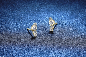 Detailansicht goldener S925 Silberohrstecker mit vier Moissanit-Steinen im Verlauf