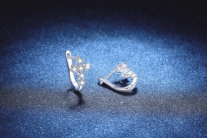 Vue macro de boucles d'oreilles créoles croix en argent 925 avec moissanite brillante