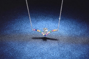 Macro detail of S925 silver V-shaped pendant with a teardrop moissanite and colorful gems