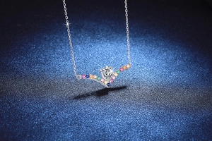 Macro detail of S925 silver V-shape necklace with colorful gems and teardrop moissanite