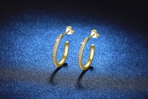 Macro detail of gold C-shape hoop earrings with micro-paved cubic zirconia stones