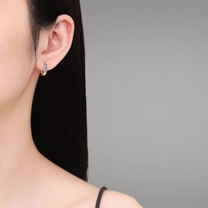 Elegant gold hoop earrings with three blue round-cut moissanite stones on model