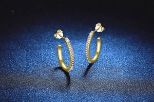 Macro detail of gold S925 silver C-shaped hoop earrings with sparkling pave moissanite