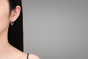 Close-up of golden hoop earrings with sparkling pave-set stones worn by a model