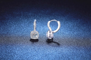 Macro view of S925 silver huggie earrings featuring a 1ct cushion-cut moissanite halo