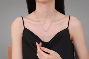Gros plan d'un collier pendentif en V en argent et moissanite D porté par un mannequin