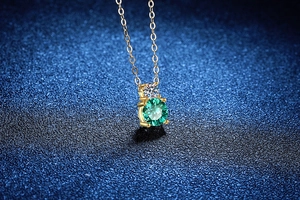 Vue macro d'un collier en argent S925 doré avec pendentif rond en moissanite vert émeraude