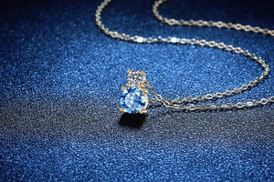 Vue macro du pendentif en moissanite bleue et blanche sur chaîne en argent doré
