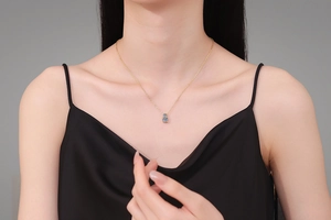 Gros plan d'un collier en argent S925 doré avec pendentif moissanite bleu clair sur modèle