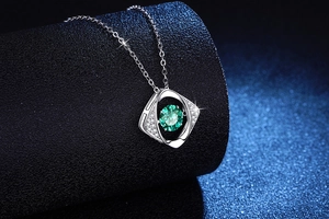 Detail of square silver pendant featuring a vibrant green center stone and tiny zircon accents
