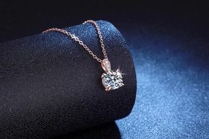 Detail of rose gold moissanite necklace with 4-prong setting on a jewelry display stand