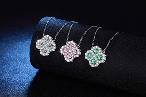 Macro shot of silver clover necklaces with white, pink, and green moissanite stones