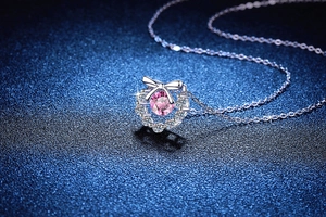 Vue détaillée du pendentif nœud en argent S925 avec une moissanite rose sur fond bleu