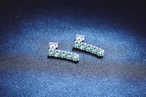 Macro shot of silver studs featuring five brilliant round green moissanite stones
