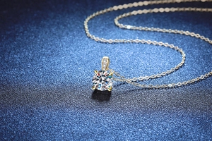 Macro view of 1ct D color moissanite pendant with four-claw setting on gold chain