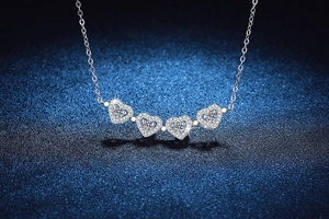 Macro detail of silver four-leaf clover heart pendant with round moissanite gemstones