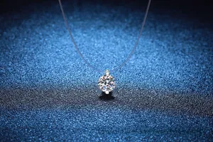 Detail showing a moissanite waterdrop pendant with invisible fishing line on a blue background