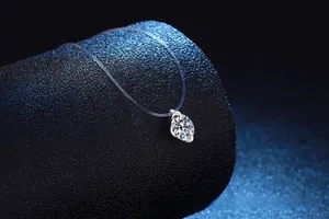Macro shot of oval moissanite pendant on invisible fishing line against dark background