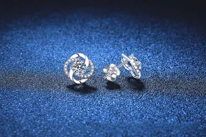 Vue macro de boucles d'oreilles trèfle en argent S925 et moissanite sur fond bleu