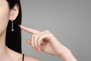 Boucles d'oreilles pendantes en moissanite sur mannequin avec une gemme ronde étincelante