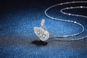 Macro shot of silver butterfly pendant with pear-cut crystals on a dark blue background