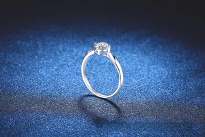 Macro view of 1 carat moissanite ring with four-prong setting on starry blue background