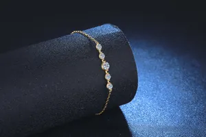 Close-up of gold moissanite bracelet with five graduated round gems on black stand