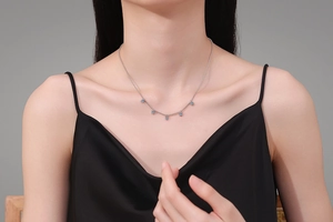 Close-up of S925 silver necklace with five blue moissanite charms on model neckline