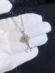 Macro detail of silver key pendant with intricate floral pattern and pavé zircons
