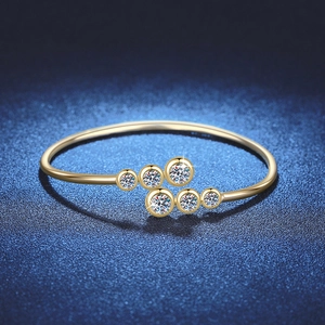 Anello aperto dorato lucido con sei gemme rotonde graduate su uno sfondo scuro
