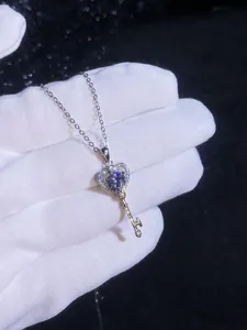 Vue macro d'un pendentif clé cœur en argent S925 avec pierre bleue sur un gant blanc
