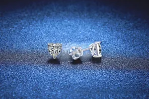 Macro detail of heart-cut moissanite earrings in 925 sterling silver on starry background