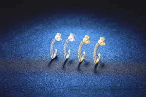 Macro shot of silver and gold C-shaped hoop earrings with micro-pave moissanite inlay