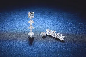 Macro detail of leaf-shaped silver earrings with sparkling moissanite and S925 tassels