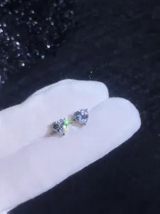 Macro view of heart-cut moissanite earrings in silver 3-prong setting on a dark background