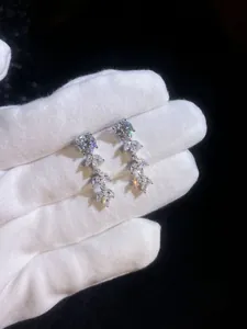 Macro view of sterling silver wheat ear tassel earrings with moissanite stones