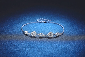 Close-up of S925 silver moissanite bracelet with heart and wing charms on blue background