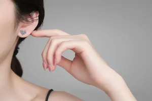 Detail view of heart-shaped S925 sterling silver earrings worn on a model's ear