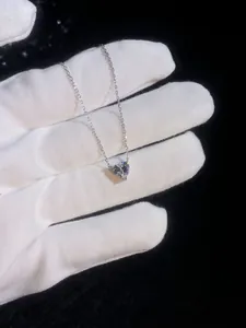 Gros plan d'un pendentif coeur en moissanite avec chaîne argent sur fond noir