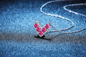Macro shot of 925 silver V-shaped heart pendant with five round rose red gemstones