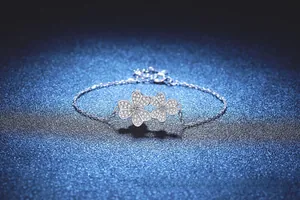 Macro shot of silver clover bracelet with sparkling diamonds on a navy starry background