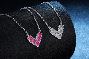 Macro shot of V-shaped heart necklaces in 925 silver with pink and white gemstones