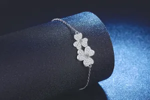 Macro shot of silver S925 clover bracelet featuring two sparkling pavé-set flower charms