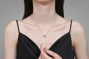Detail of V-shaped heart pendant necklace in silver with pink stone on model