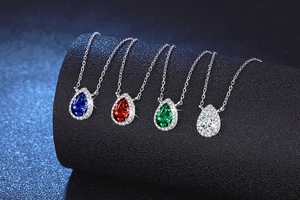 Detail of pear-shaped halo necklaces in blue, red, green and white gemstone finishes