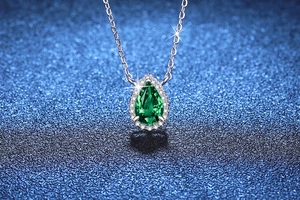 Close-up of a pear-cut emerald gemstone pendant on a silver S925 necklace chain