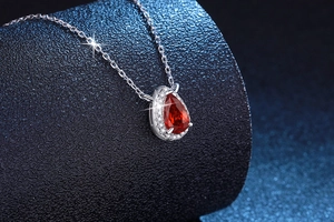 Macro view of pear-cut red ruby pendant with white zircon halo on S925 silver chain