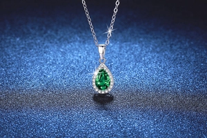 Vue détaillée d'un pendentif émeraude poire entouré de diamants sur chaîne en argent