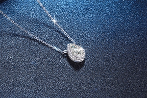 Macro shot of S925 silver necklace with pear-cut gemstone and halo diamond settings