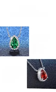 Macro detail of pear-cut emerald and ruby pendants with diamond halo on silver chain